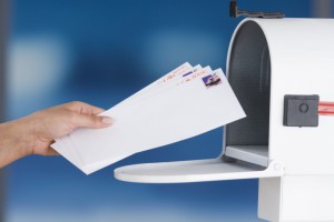 Hands placing envelopes in mailbox